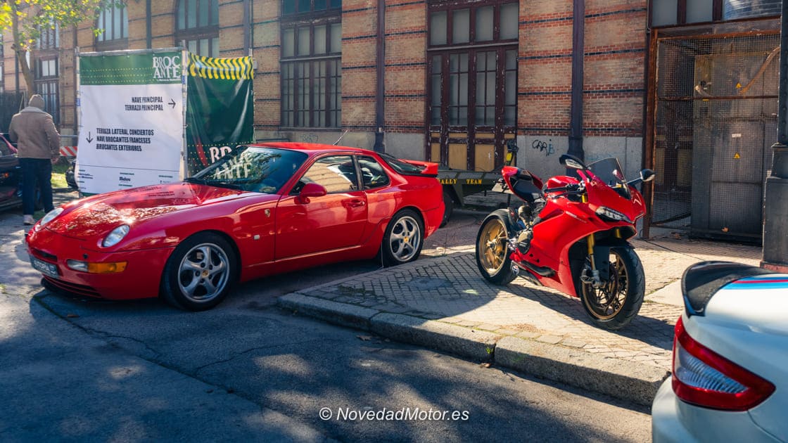 Porsche clásico rojo y moto Ducati roja aparcados juntos en Autopía en Brocante en el Museo del Ferrocarril